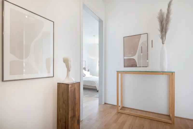 Flur mit Holzparkett, Konsole aus Holz und Wandbildern, Blick in das Schlafzimmer