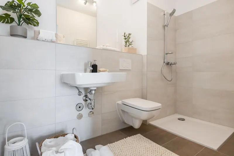 Duschbad mit bodengleicher Dusche, Waschbecken, Spiegel und wandhängendem WC