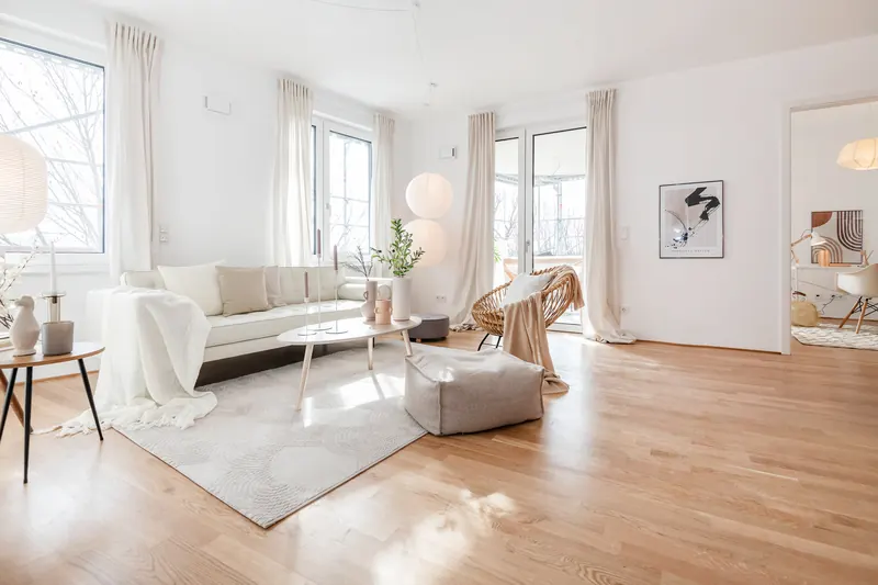 Großzügiges Wohnzimmer mit Sofa, Couchtisch, Teppich und mehreren Fenstern