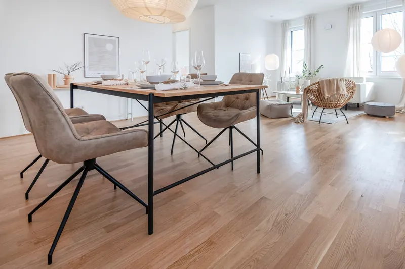 Essbereich mit Holztisch und Polsterstühlen, im Hintergrund das helle Wohnzimmer