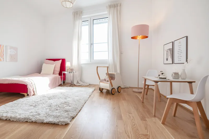 Wohn- und Schlafraum mit Tagesbett, Teppich, Tisch mit Stühlen und Stehleuchte