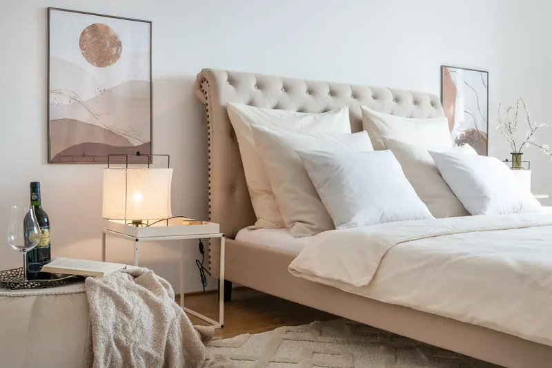 Bett mit Kissen, Nachttisch mit Leuchte und Wandbild