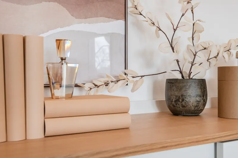 Sideboard mit Büchern, Glasflakon und Zweigen in einer Vase