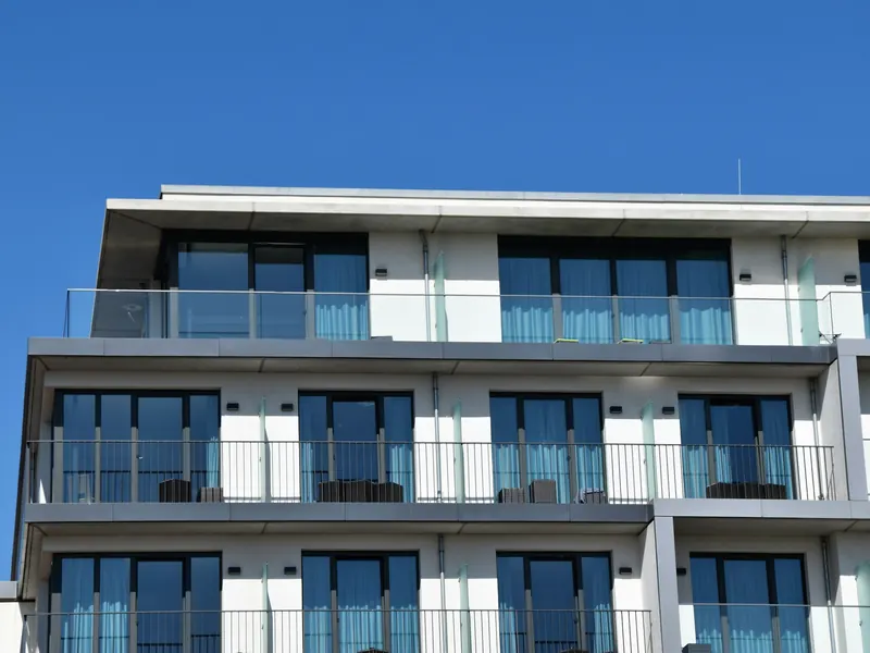 Helle, moderne Wohnanlage mit verglasten Balkonen vor blauem Himmel