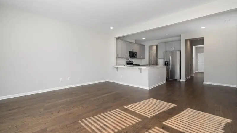 Leere, helle Wohnung mit Holzboden und offener Küche im Hintergrund