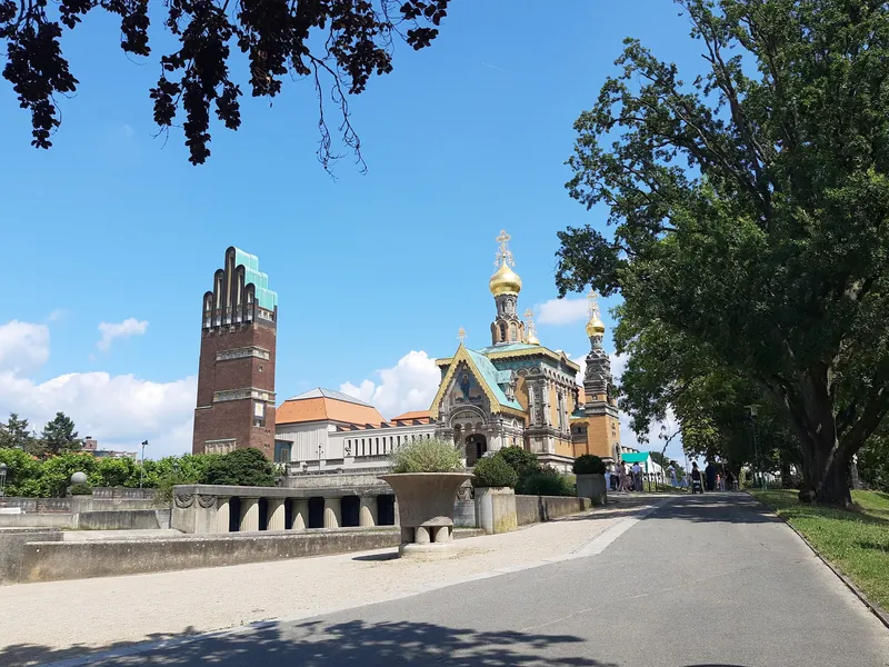 Mathildenhöhe in Darmstadt mit Hochzeitsturm und Russischer Kapelle unter blauem Sommerhimmel, rechts große Bäume