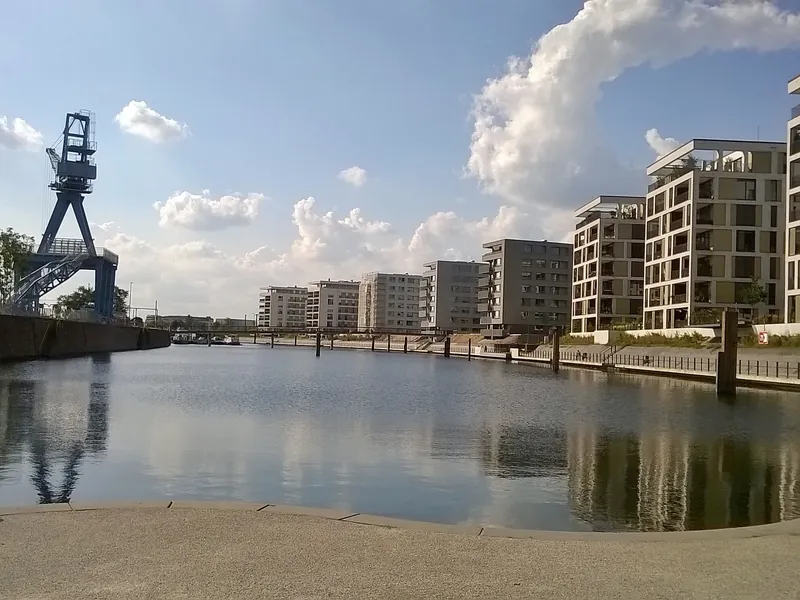 Hafenbecken in Offenbach am Main mit neuen hellen Wohngebäuden am Ufer und einem historischen Hafenkran
